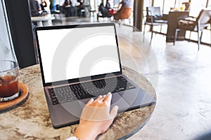 A hand touching on laptop computer touchpad with blank white desktop screen on the table