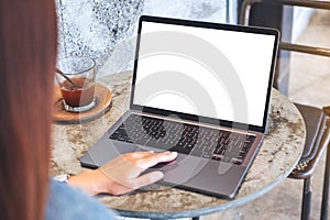 A hand touching on laptop computer touchpad with blank white desktop screen on the table