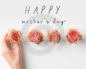 hand touching pink rose buds placed in row with HAPPY MOTHERS DAY inscription isolated on white