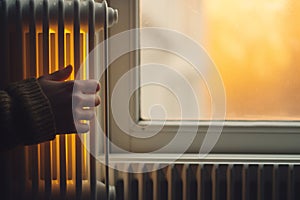 A hand touching white radiator of a central heating system, checking the temperature of a heater, warm and cozy home