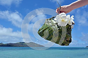 Hand of a tourist woman carry a Fijian basket made out of coconut tree leaves