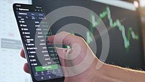 Hand of Trader Touching Display of Stock Market Quotes on Smartphone. Online Trading on Computer. Economic and Finance