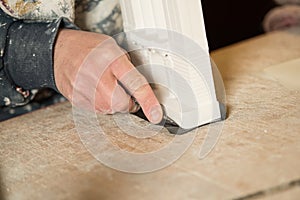 Hand with Trimming Blade Cutting Black Paper on Model Base