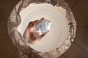 Hand trowing a paper into a wastebasket, inside view