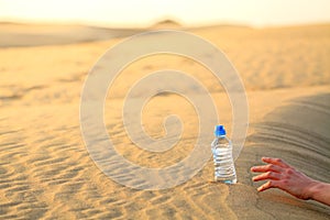 Hand try to catch the bottle of water on sand desert