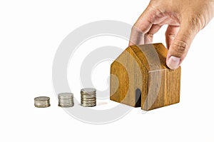 hand try to pick up wooden toy house with coins concept of dearness of habitation photo