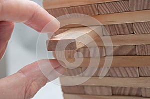 Hand try to take off piece of wooden brick of construction game