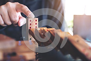 A hand trying to stop wooden domino game from falling on table