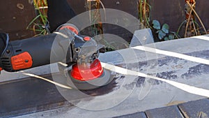 Hand with a turbine removes rust from metal. man using angle grinder