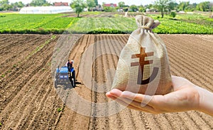 Hand with a Turkish lira money bag on the background of a farm field with a tractor. Subsidies support for agricultural producers