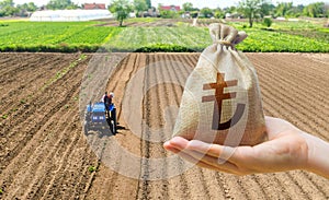 Hand with a Turkish lira money bag on the background of a farm field with a tractor. Subsidies support for agricultural producers photo