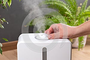 Hand turn on aroma oil diffuser at home  steam from the air humidifier  free space. Ultrasonic technology  increase in air