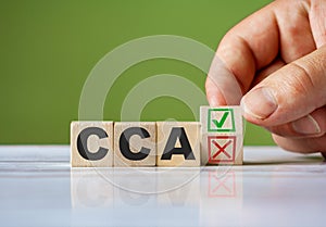 The hand turn wooden block with red reject X and green confirm tick as change concept of CCA. Word CCA - Current Cost Accounting