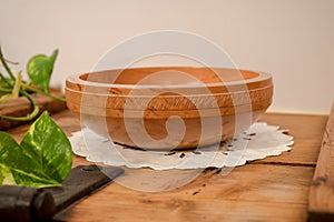 A hand-turned wooden bowl made of light pearwood with all-round decoration stands on a wooden board