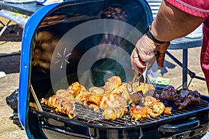 Hand Turning Barbecued Chicken over a Grill
