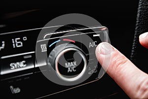 Hand turning on car air conditioning system.