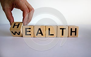 Hand is turning a cubes and changes the word `health` to `wealth` or vice versa. Beautiful white background, copy space. Busin