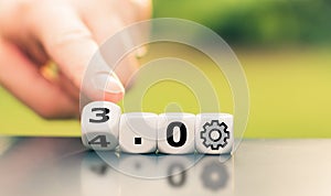 Hand is turning a dice and changes the expression `Industry 3.0` to `Industry 4.0.