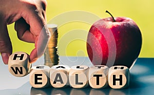 Hand is turning a dice and changes the word `health` to `wealth`. photo