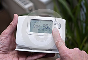 Hand turning down temperature on digital central heating controller