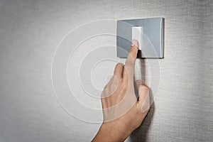 Hand turning on or off on grey light switch with textur