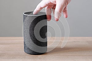 Hand turning off smart speaker microphone photo