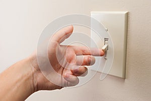 Hand turning wall light switch off.