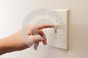 Hand turning wall light switch off.