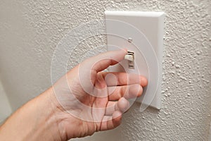 Hand turning wall light switch off