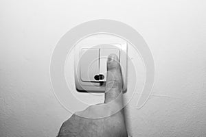 Hand turning the wall light switch on/off. Light switch close up