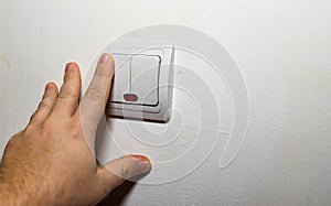 Hand turning the wall light switch on/off. Light switch close up