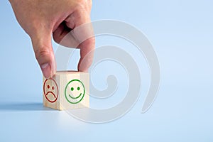 Hand turning a wooden block With Happy and Unhappy Face