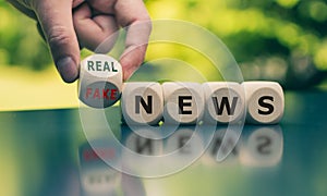 Hand turns a cube and changes the expression `fake news` to `real news`