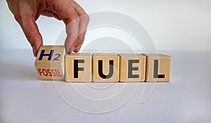 Hand turns a cube and changes the expression `fossil fuel` to `H2 fuel`. Beautiful white background, copy space. Concept