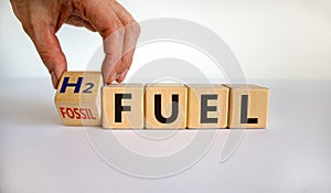 Hand turns a cube and changes the expression `H2 fuel` to `fossil fuel`. Beautiful white background.  Copy space