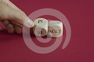 Hand turns a cube and changes the word result and insult. Beautiful red background. Symbol that a result is an insult photo