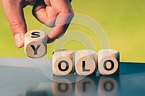 Hand turns a cube and changes the word `solo` to `yolo`
