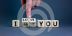 Hand turns cubes and changes the expression `I hate you` to `I love you`. Beautiful grey background, copy space. Concept