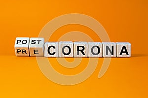 Hand turns cubes and changes the expression `pre corona` to `post corona`. Covid-19 pandemic concept. Beautiful orange backgro