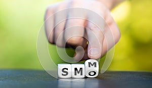 Hand turns dice and changes the abbreviation SMO social media marketing to SMM social media optimization