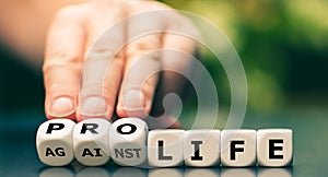 Hand turns dice and changes the expression `against life` to `pro life`.