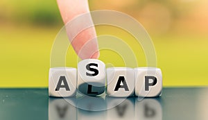 Hand turns a dice and changes the expression `ALAP` as late as possible to `ASAP` as soon as possible, or vice versa. photo