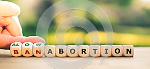 Hand turns dice and changes the expression `ban abortion` to `allow abortion`, or vice versa.