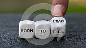 Hand turns dice and changes the expression `born to follow` to `born to lead`.