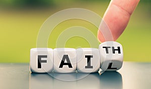 Hand turns a dice and changes the expression `fail` to `faith`, or vice versa. photo