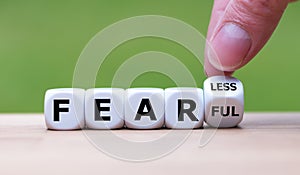 Hand turns a dice and changes the expression `fearful` to `fearless`. photo