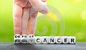 Hand turns dice and changes the expression `fight cancer` to `defeat cancer`.