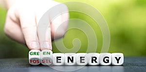 Hand turns dice and changes the expression `fossil energy` to `green energy`. photo