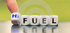 Hand turns a dice and changes the expression `fossil fuel` to `H2 fuel.