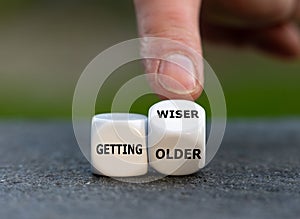 Hand turns dice and changes the expression `getting older` to `getting wiser`.